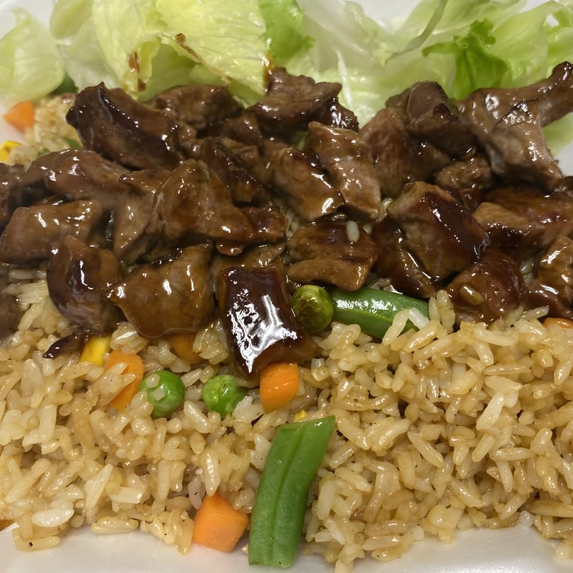Teriyaki beef with fried rice, green beans, carrots, peas, and a side of lettuce.